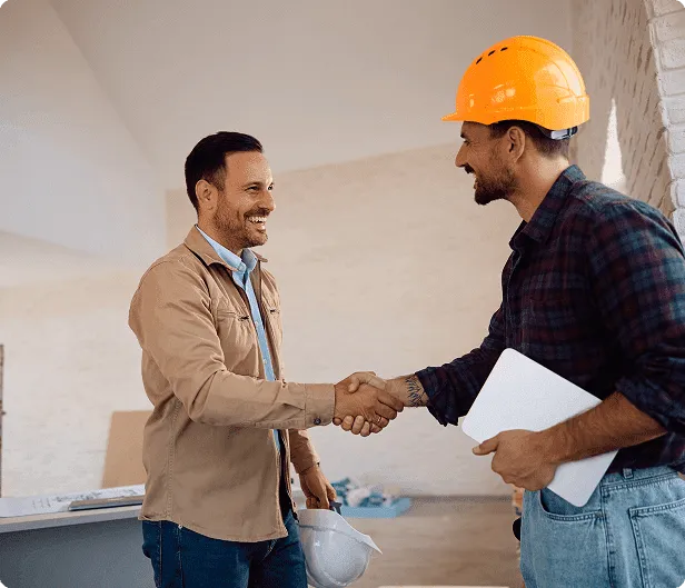 Two men shaking hands at construction site.