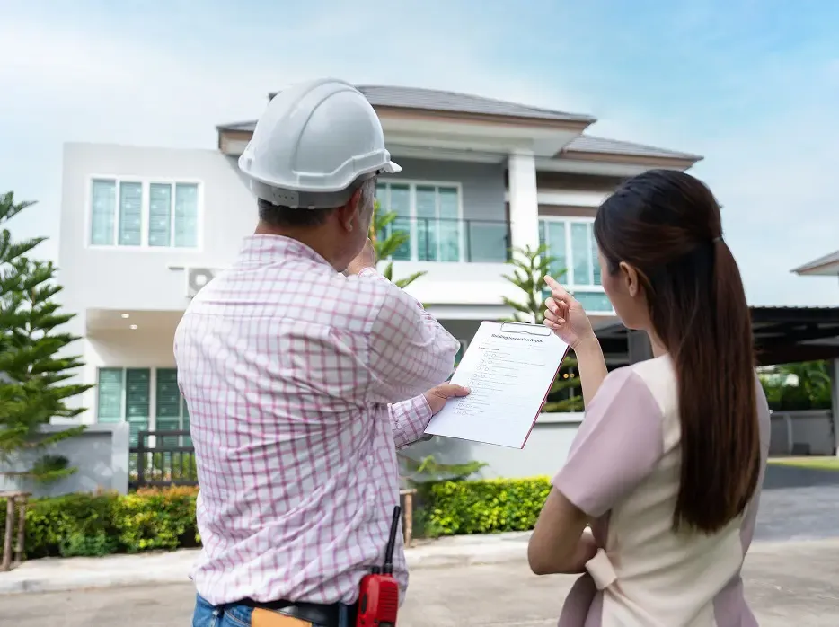 Inspector and woman reviewing house checklist outside.